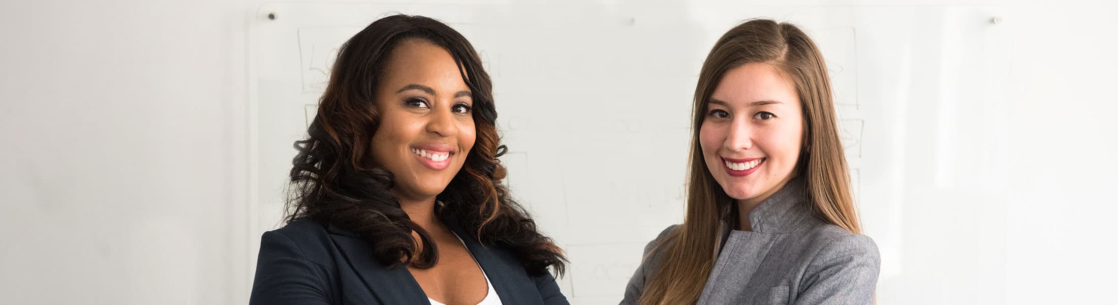 two young professional women standing and smiling
