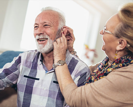 women putting a hearing aid on a man