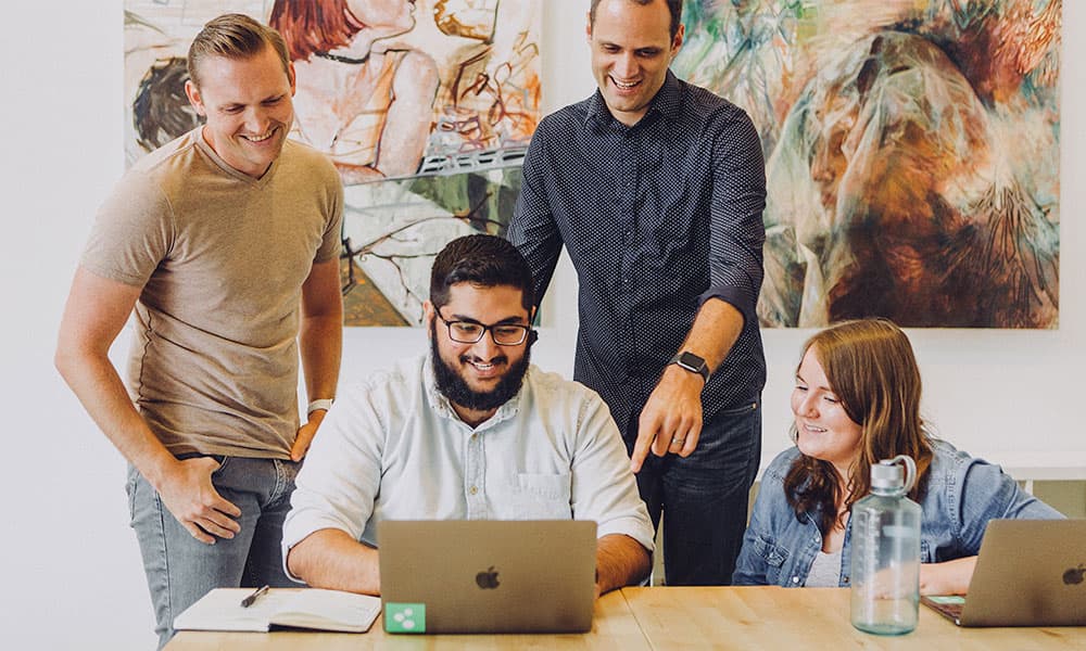 a group of young professionals looking at a laptop