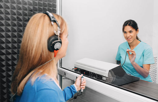women getting ear tested behind glass